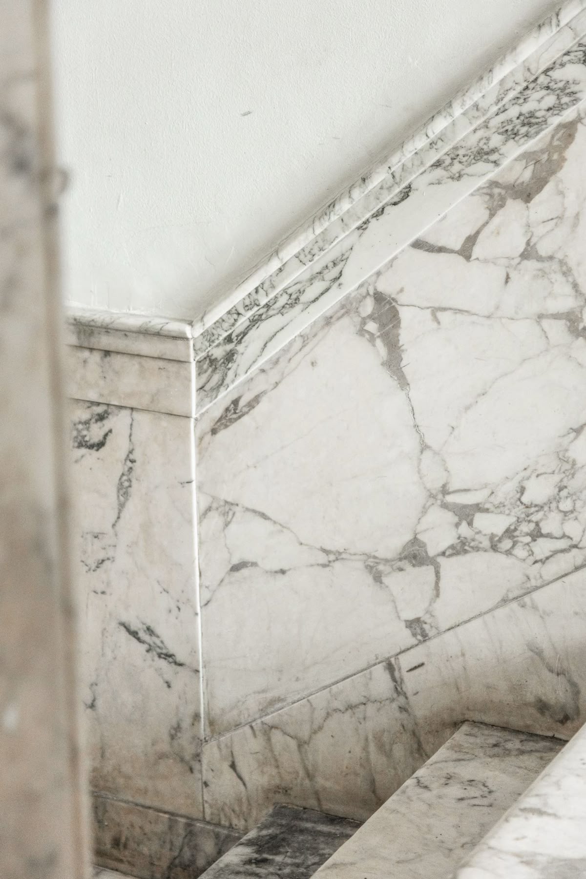 White marble staircase wall with a moulded marble dado rail